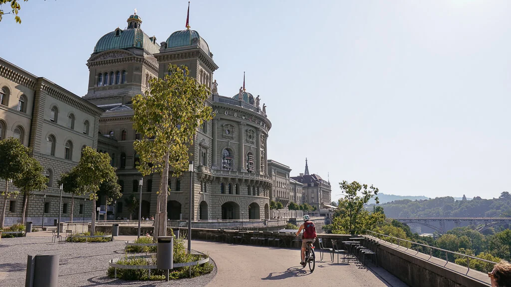 Couchflucht fährt mit dem E-Bike auf der Terrasse des Bundeshauses in Bern.