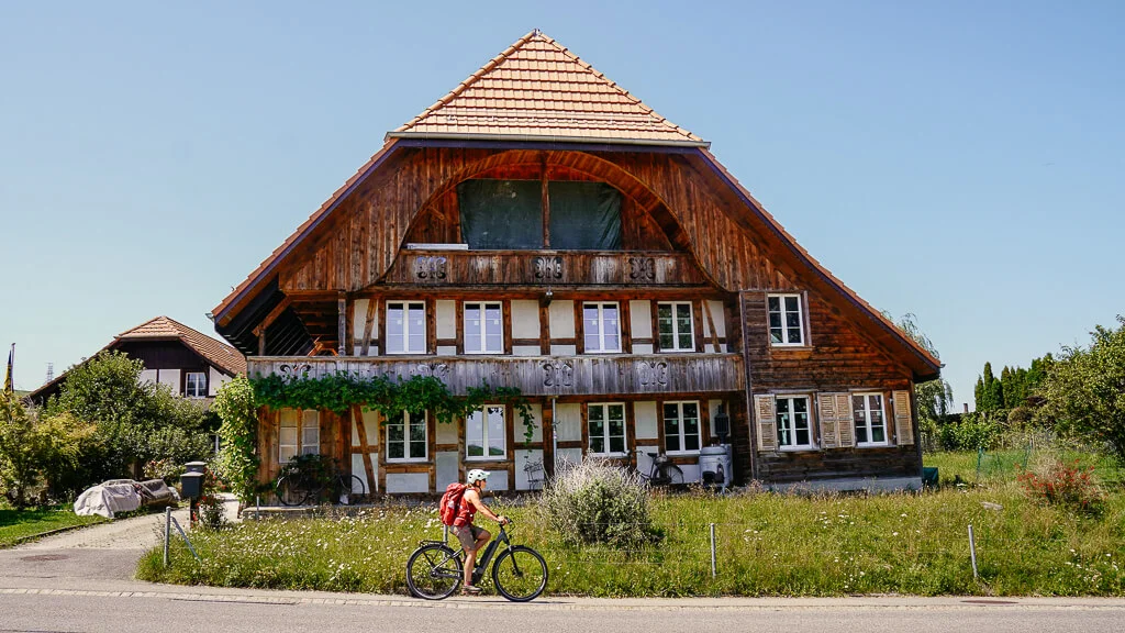 Naturpark Gantrisch - E-Bike Tour auf der Sagenroute - Couchflucht fährt an einem Bauernhaus vorbei